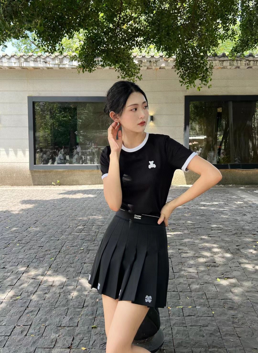 Chân váy ngắn đen, logo ở gấu