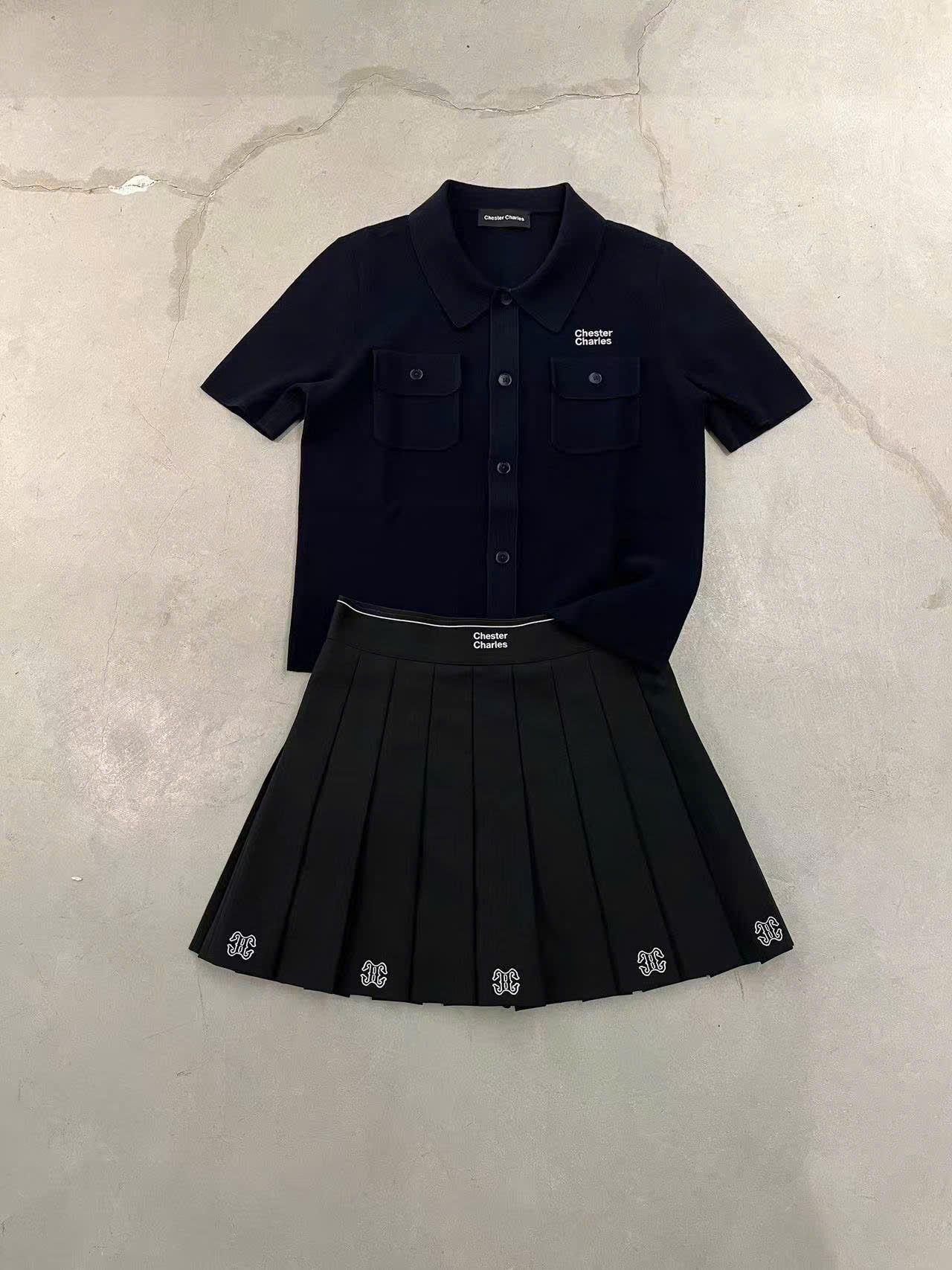 Chân váy ngắn đen, logo ở gấu