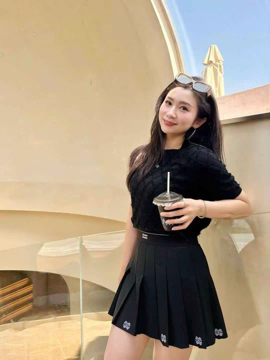 Chân váy ngắn đen, logo ở gấu