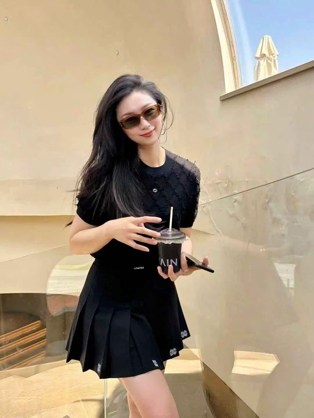 Chân váy ngắn đen, logo ở gấu