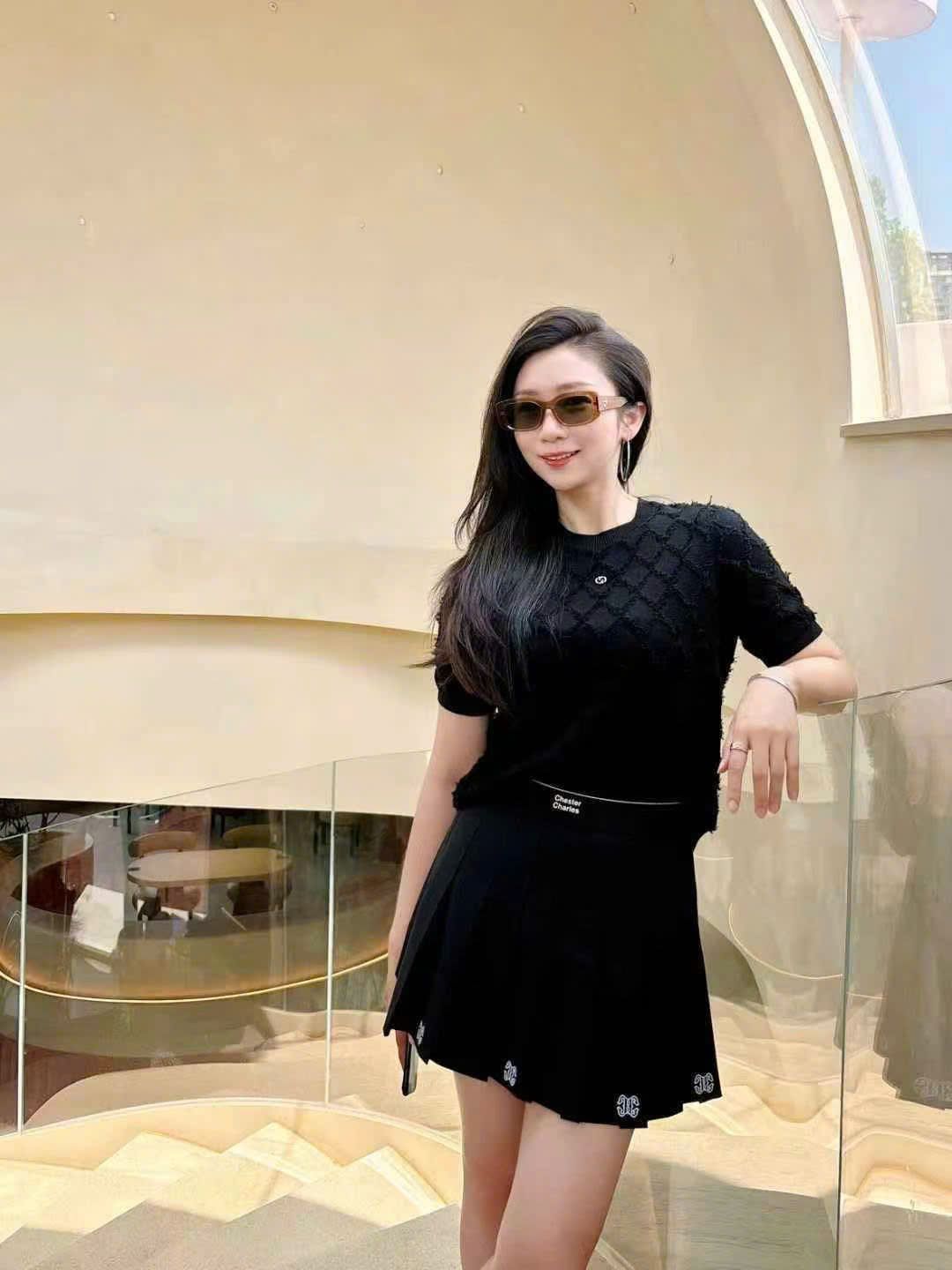 Chân váy ngắn đen, logo ở gấu