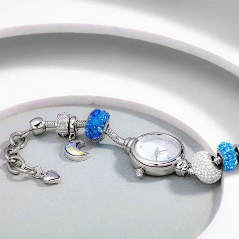  Saga Charm 53229-SVMWSV-8 – Nữ – Đính đá Swarovski lấp lánh – Mặt số khảm xà cừ cùng hiệu ứng chuyển sắc – Dây charm màu bạc đan xen sắc xanh dương 