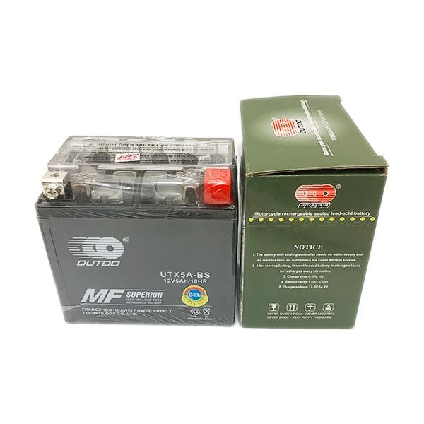 Bình ắc quy OUTDO UTX5A-BS 12V 5AH bên cạnh vỏ hộp xanh, tem MF Superior và hướng dẫn sử dụng
