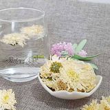 Hoa cúc trắng nở trong ly nước thủy tinh, bên cạnh là đĩa đựng hoa cúc trắng khô và cành hoa trang trí, tạo cảm giác thư thái.