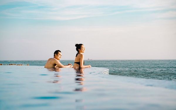 hồ bơi nhìn ra biển có 2 người một đàn ông một phụ nữ