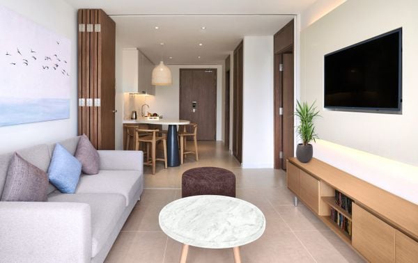 bộ sofa xám bên trái và bàn gỗ nhỏ, bên phải trên tường treo tv