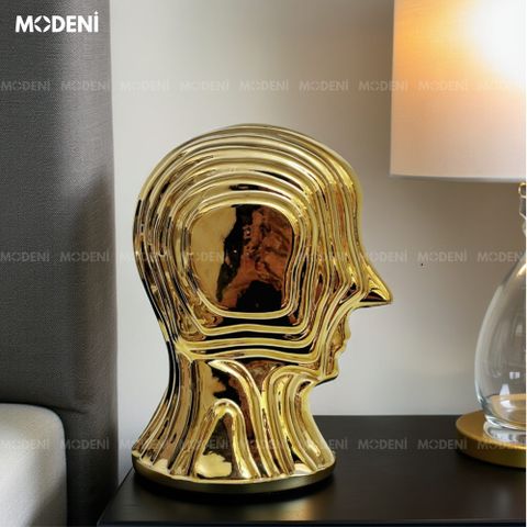 Decor tượng Vantis Gold đặt trên bàn đầu giường – nổi bật trong ánh đèn vàng ấm áp.
