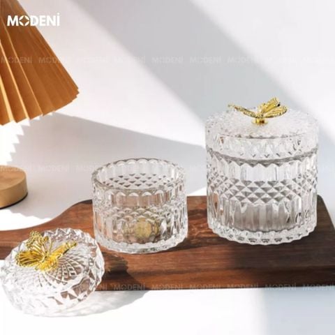 Lọ Iris Retro Pháp đặt trên bàn trắng, nắp bướm vàng nổi bật dưới ánh nắng.