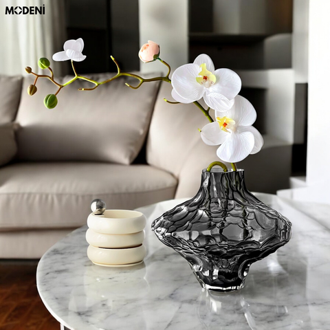 Bình hoa thủy tinh Moss đặt trên bàn trắng, phối lan trắng tinh tế – phong cách hiện đại nghệ thuật.