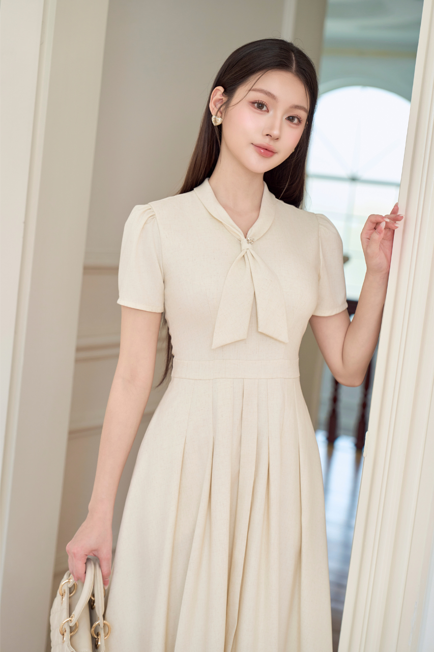 Váy nữ dài dáng xòe xếp ly có túi cổ thắt nơ cách điệu ngắn tay màu kem vải vân tiêu YAME YV635