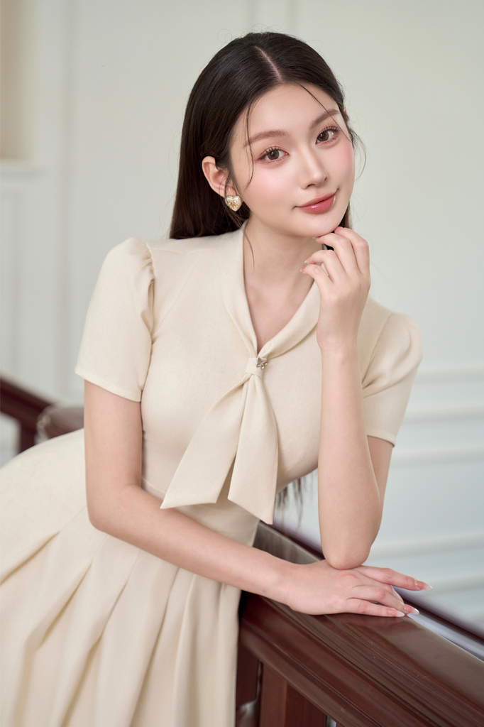Váy nữ dài dáng xòe xếp ly có túi cổ thắt nơ cách điệu ngắn tay màu kem vải vân tiêu YAME YV635