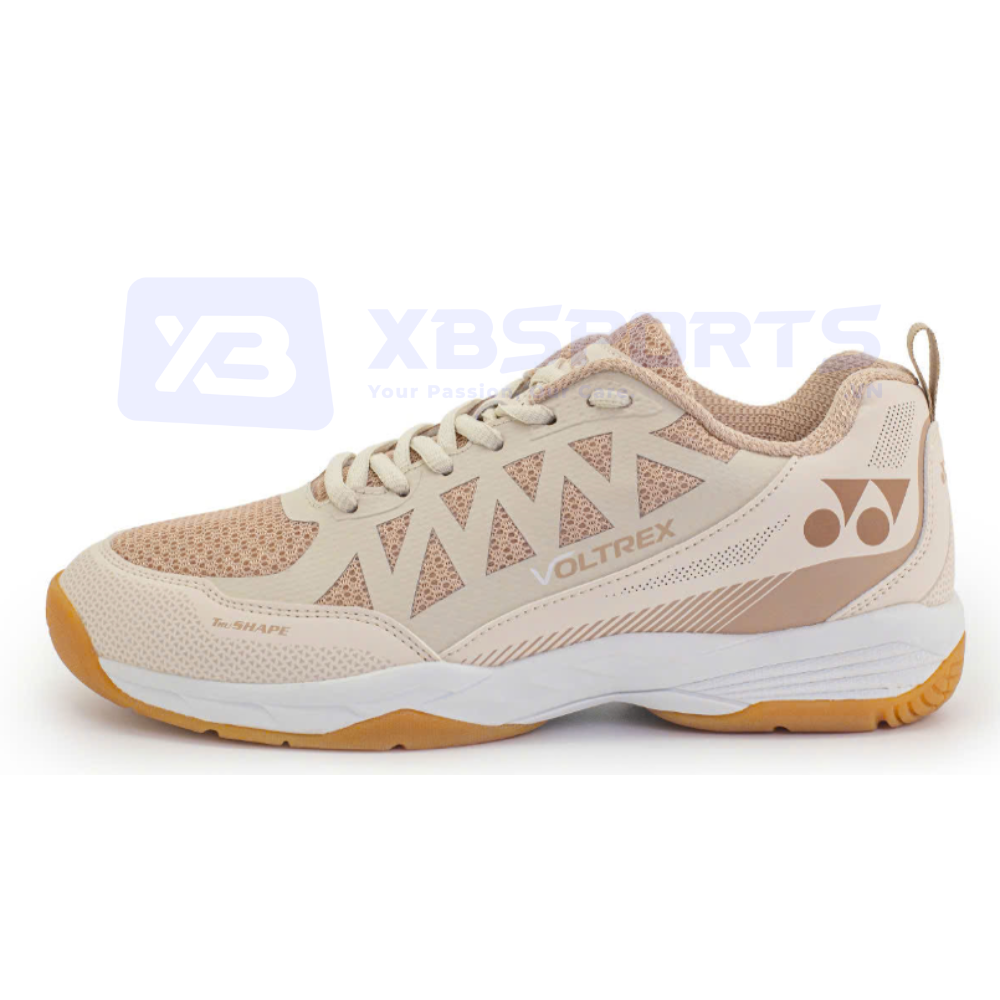 Giày cầu lông Yonex Voltrex màu be phối vàng đồng, thân lưới be có họa tiết tam giác, chữ VOLTREX và Tru SHAPE màu đồng, logo YY vàng đồng ở gót, đế giữa trắng và đế ngoài gum caramel